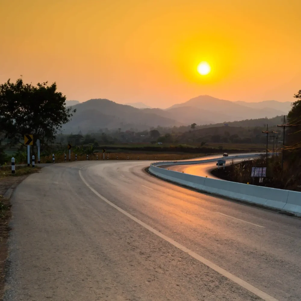 road-by-trees-against-orange-sky-sunset